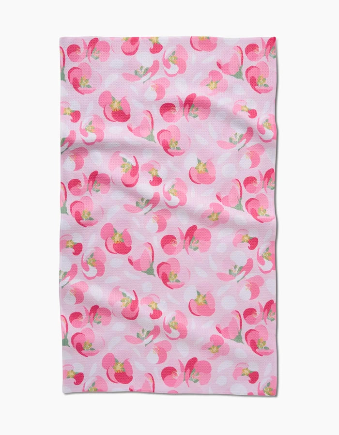 The Cherry Blossom by Rebecca Bobko is a cloth towel made from ultra-absorbent Geoweave fabric, with a pink background and abstract pink and red florals accented with green and yellow. Slight fabric wrinkles are visible.