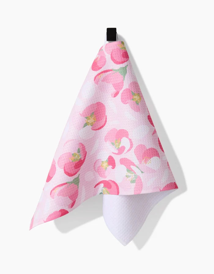The Cherry Blossom bar towel by Rebecca Bobko showcases large pink floral patterns with green accents, hanging from a black loop. Made from Geoweave fabric, it offers both softness and durability against a white background.