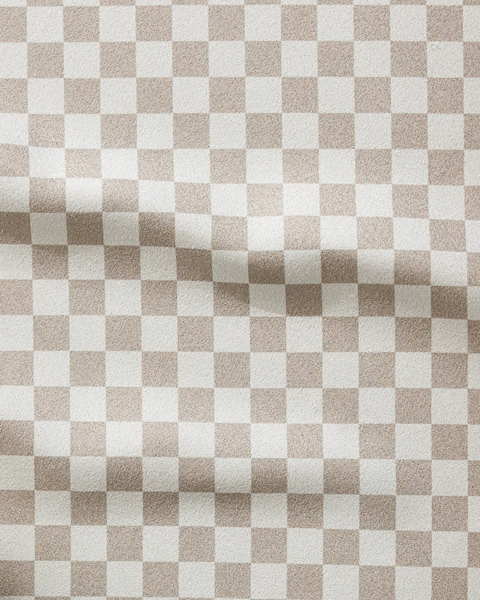 The GEOMETRY Chic Checker fitness towel features a wavy beige and white checkerboard pattern, offering a subtle textured look. Made from recycled materials, this ultra-absorbent towel is both stylish and eco-friendly.