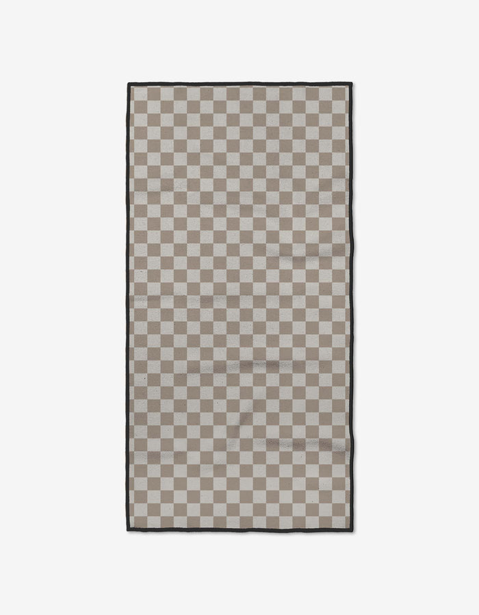 The GEOMETRY Chic Checker is a rectangular fitness towel featuring a beige and light gray checkerboard design with a slim black border, made from soft Geoweave fabric, shown on a plain white background.