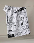 The Elisabeth Wing "Chicago" tea towel features black-and-white illustrations of the skyline, a lion, Chicago Theater, boat, clouds, and people. Made from recycled materials and shown hanging on a line against a neutral background.