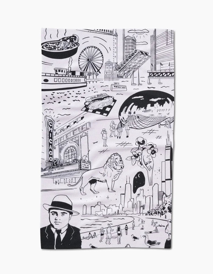 The Chicago Tea Towel by Elisabeth Wing features black line drawings of iconic city landmarks on white Geoweave fabric, capturing scenes with people and buildings, including the Bean, Ferris wheel, deep dish pizza, lions, skyline, and more.