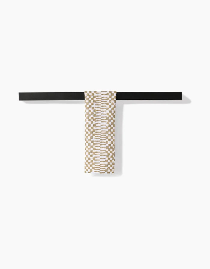 A Chutes Avocado bar towel by Studio Jeannot, featuring a patterned beige and white Geoweave fabric, hangs neatly over a sleek black bar against a plain white background.