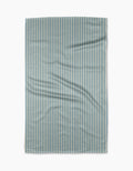 The Clean Slate tea towel by Susan Heid is rectangular, made from recycled materials, with thin blue and white vertical stripes and a slightly wrinkled texture, shown against a white background.