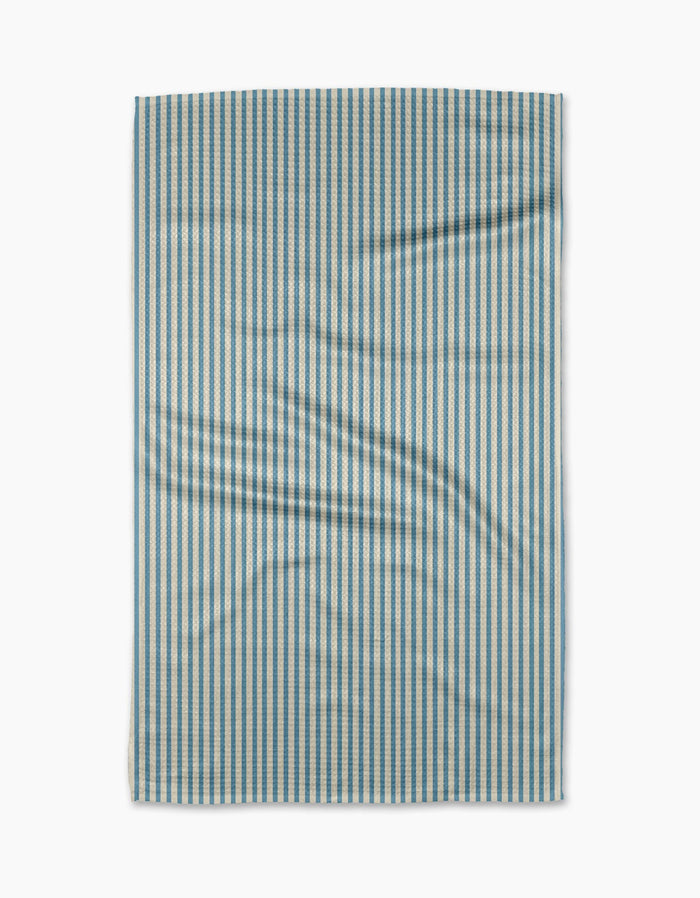 The Clean Slate tea towel by Susan Heid is rectangular, made from recycled materials, with thin blue and white vertical stripes and a slightly wrinkled texture, shown against a white background.