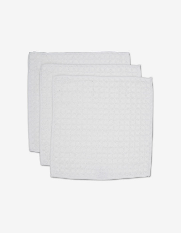 Three white, rectangular GEOMETRY Cloud waffle washcloths with a textured pattern are stacked on a white background, adding spa-like comfort and luxury to your towel collection.