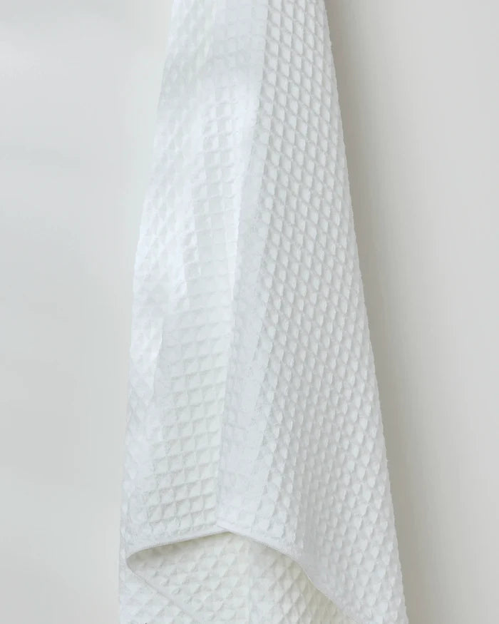The GEOMETRY Cloud bath towel, featuring a textured waffle pattern, hangs against a plain white wall.