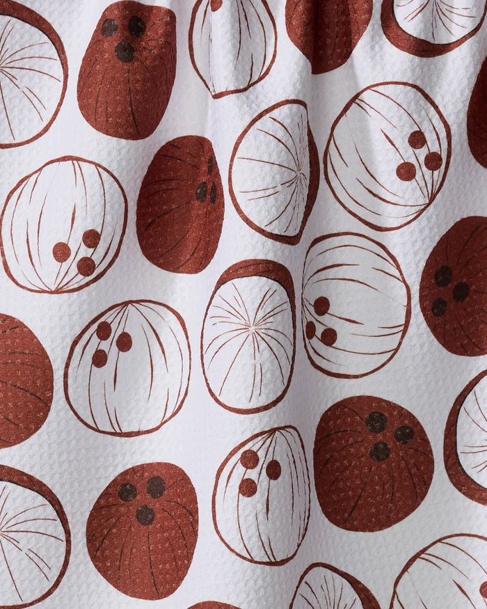 The Sara Mari "Coconutz About You" ultra-absorbent tea towel features white fabric with a repeating pattern of brown and dark brown coconuts, some whole, some with coconut "eyes," making it a stylish, practical addition to your kitchen.