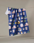The Coffee Drinks kitchen towel by Cottonflower Studio is blue, made from recycled materials, and features colorful mugs, cups, teapots, and desserts hanging on a clothesline against a neutral background.