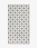 The Collins Luxe Bath Towel by Charlie Rowan Designs is a white rectangular towel featuring a repeating geometric grid of black squares and dots, crafted using innovative Geoweave technology for symmetry and style.