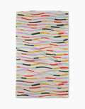 The Geometry Colorful Currents blanket features wavy, multicolored lines and rectangles in orange, pink, green, yellow, blue, and red on a light beige background. Its crafted from post-consumer recycled materials.