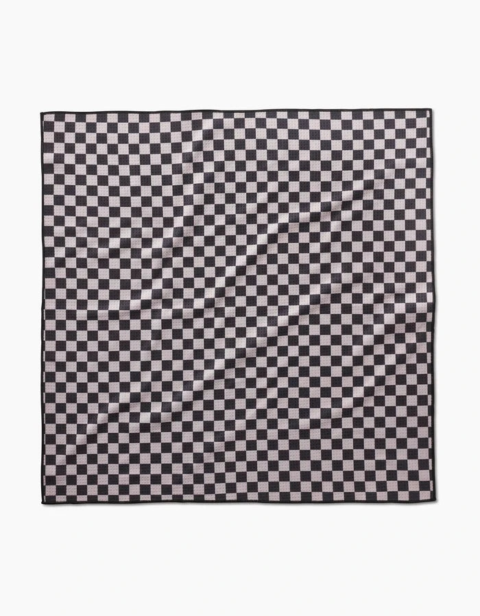 The Geometry Cool Pup dog towel in black and white checkered pattern lays flat, showing a wrinkled, highly absorbent surface with repeating squares.
