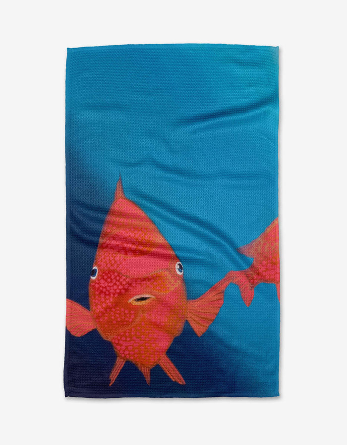 Coral Glow by Trey Jolley: a blue tea towel made from recycled materials, featuring a large orange-red fish with wide eyes, small mouth, and part of another fish on the right edge.