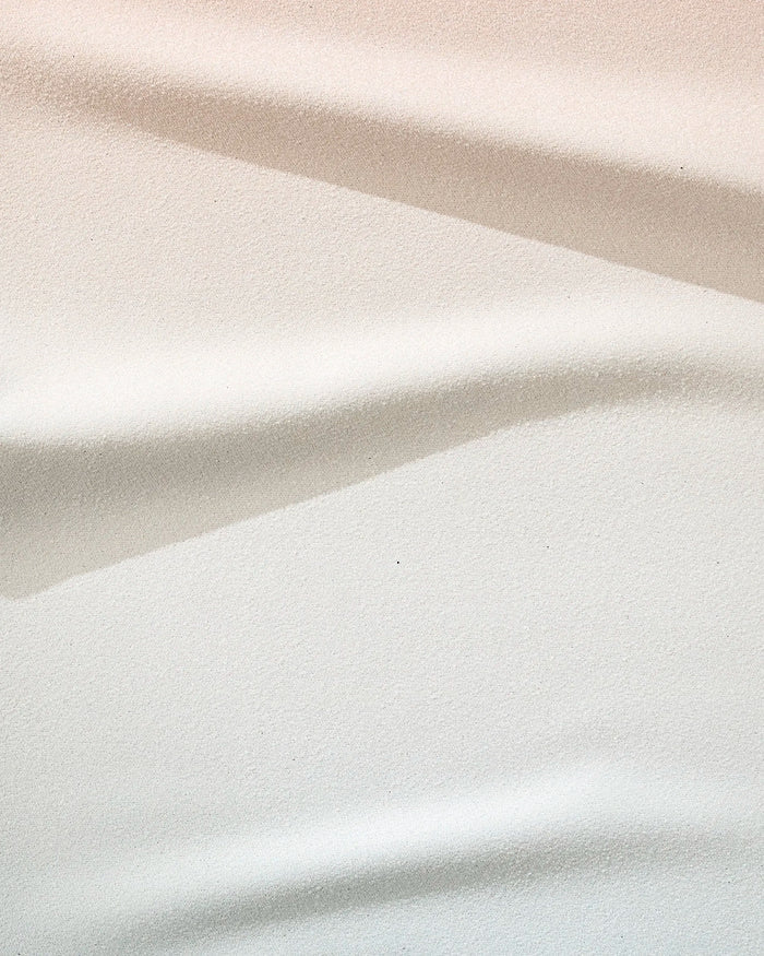 Close-up of the GEOMETRY Core towel in soft white, beige, and light grey tones with striped folds—ultra-absorbent and crafted from recycled materials.