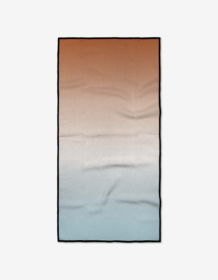 The GEOMETRY Core is a rectangular fitness towel made from Geoweave fabric, shown flat on a white background with a gradient design shifting from warm reddish-brown to beige and light blue.