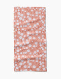 The Cotton Floral bar towel by Coit Creative features a peach hue with white dots and red lines forming abstract flowers. Made from ultra-absorbent Geoweave fabric, it’s shown laid flat with gentle wrinkles.