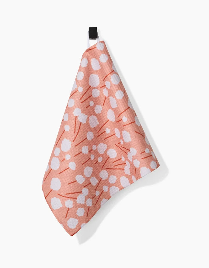 The Coit Creative Cotton Floral is a pink kitchen towel made from ultra-absorbent Geoweave fabric, featuring a white abstract dotted pattern and a black hanging loop, shown against a white background.