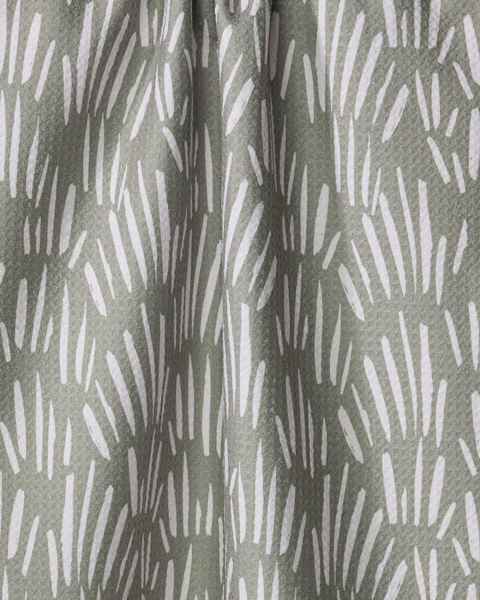 Close-up of Hufton Studio’s "Country Fields" kitchen towel, crafted from recycled materials and adorned with white, brushstroke-like shapes on a muted green background for a textured, abstract look.