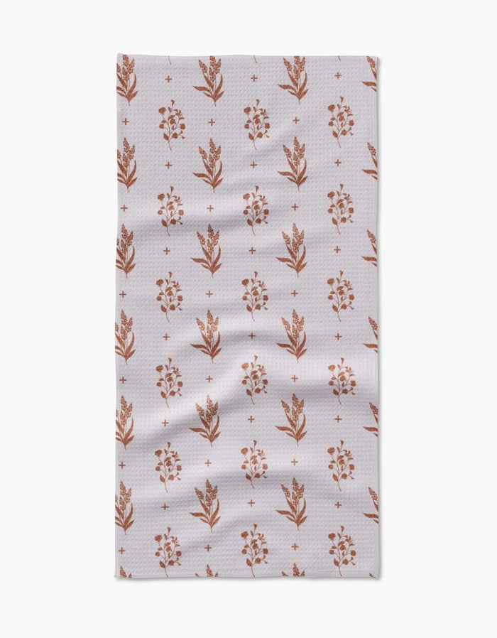 The Country Road by Charlie Rowan Designs is a rectangular Geoweave cloth with small rust floral motifs and plus signs on a light, textured background. Slight wrinkles add to the versatility of this stylish kitchen accessory.