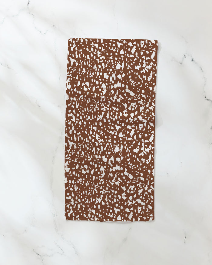 The Cowboy Horse Hide notebook by Hufton Studio, featuring a rectangular brown cover with a white speckled pattern, rests on a white marble surface next to an ultra-absorbent towel.