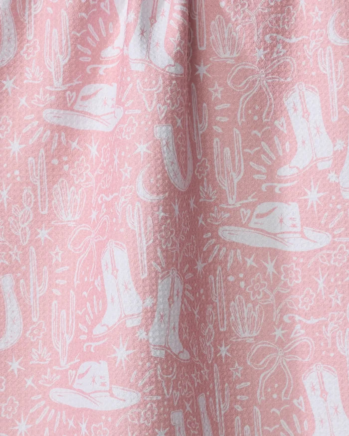 Add a touch of flair to your kitchen with the Cowgirl Chic dish towel by Aubrey Fairchild. This pink, absorbent towel features a white western motif with cowboy hats, boots, cacti, stars, and lassos in softly gathered folds.