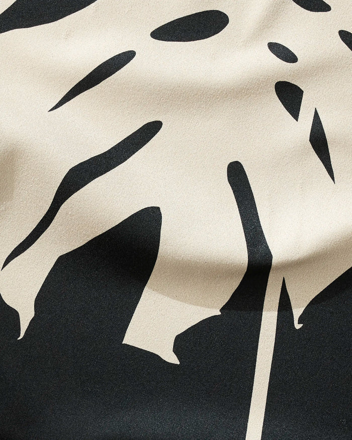 Cream Monstera by PrintedPlant features a beige and black abstract monstera leaf pattern on a textured fabric fitness towel made from recycled materials, with visible folds and shadows.