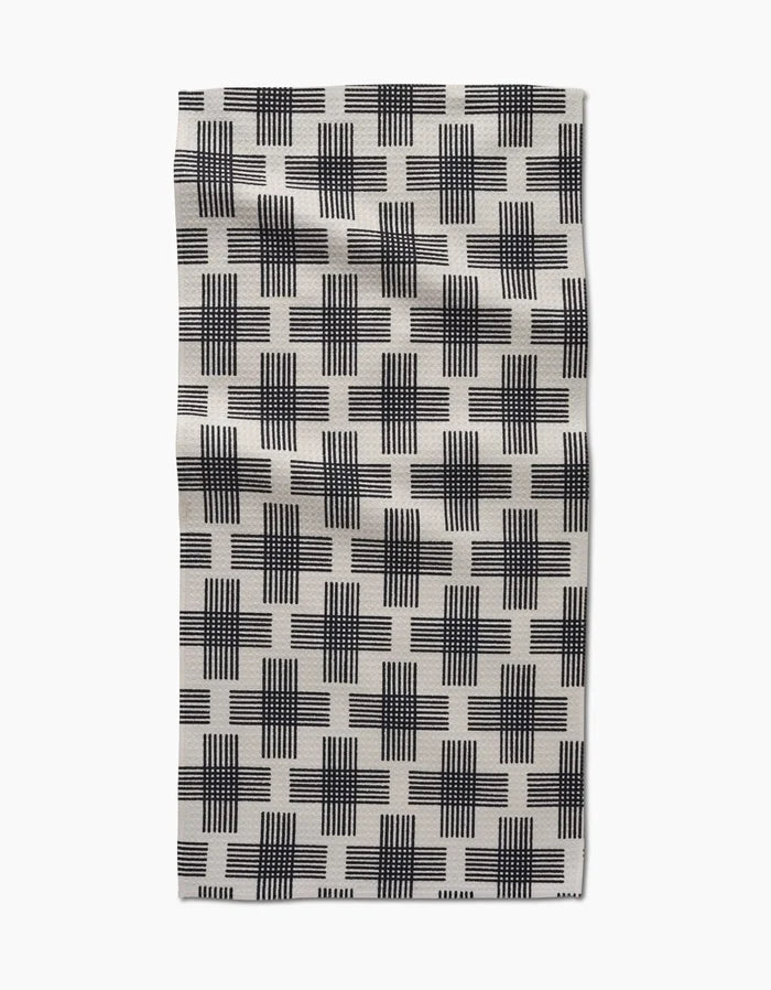 The Cross Hatch bar towel by Rosa Kichline features black and white overlapping grid-like squares on Geoweave fabric, shown flat against a white background.