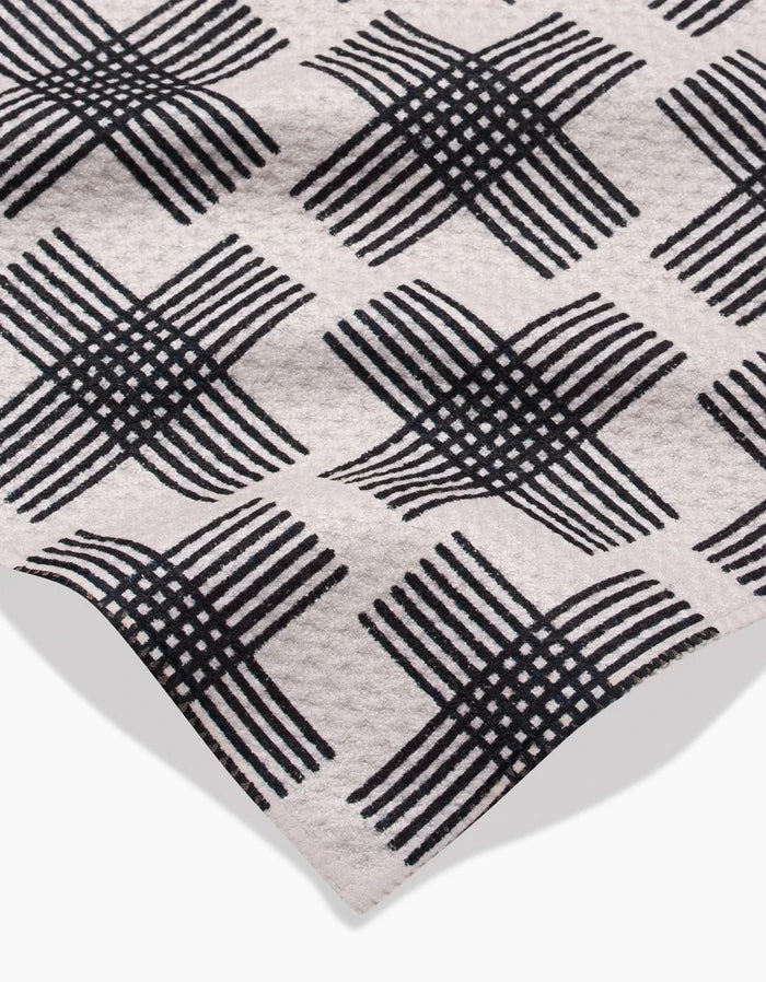 A close-up of Rosa Kichline’s Cross Hatch bar towel in beige Geoweave fabric, featuring a black diamond-patterned crisscross design. Made from post-consumer recycled materials with a folded corner and subtle texture.