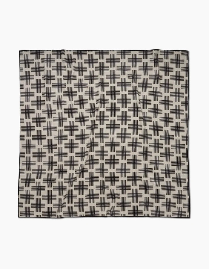 The Cross Hatch by Rosa Kichline is a square beach blanket crafted from quick-drying recycled materials, featuring a repeating black rectangular geometric pattern on beige with a thin black border.
