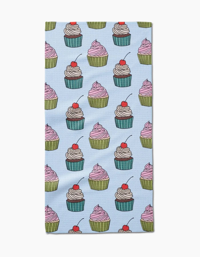 Cupcake Love by Amy Droubay is a light blue bar towel with rows of colorful cupcakes, some topped with cherries, on soft Geoweave fabric.