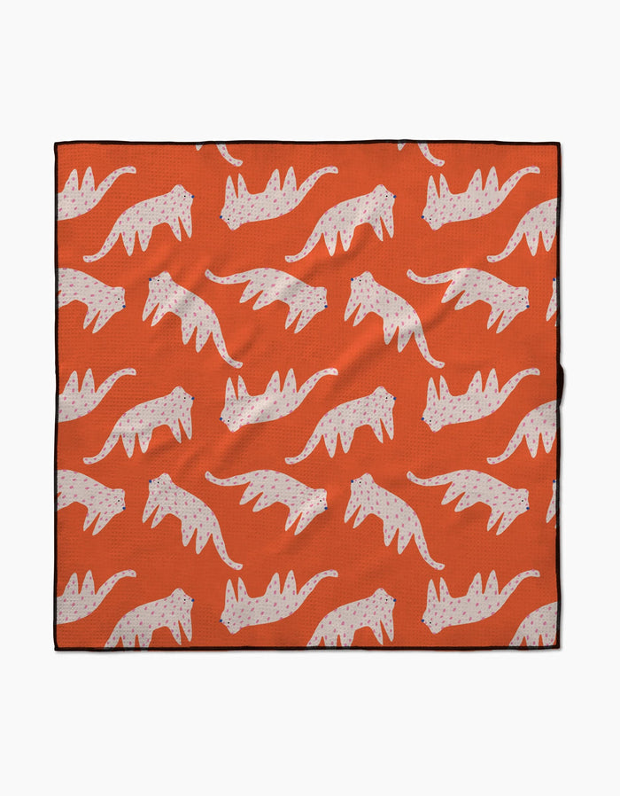 The Cute Cheetah blanket by Jennifer Bouron is lightweight and eco-friendly, featuring a repeating pattern of white cats with pink spots in a walking pose on an orange background.