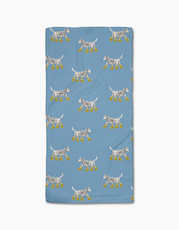 Geometry’s “Dalmatian In Boots Blue” towel features a blue, ultra-absorbent design with cartoon Dalmatian dogs in yellow rain boots on a white background.