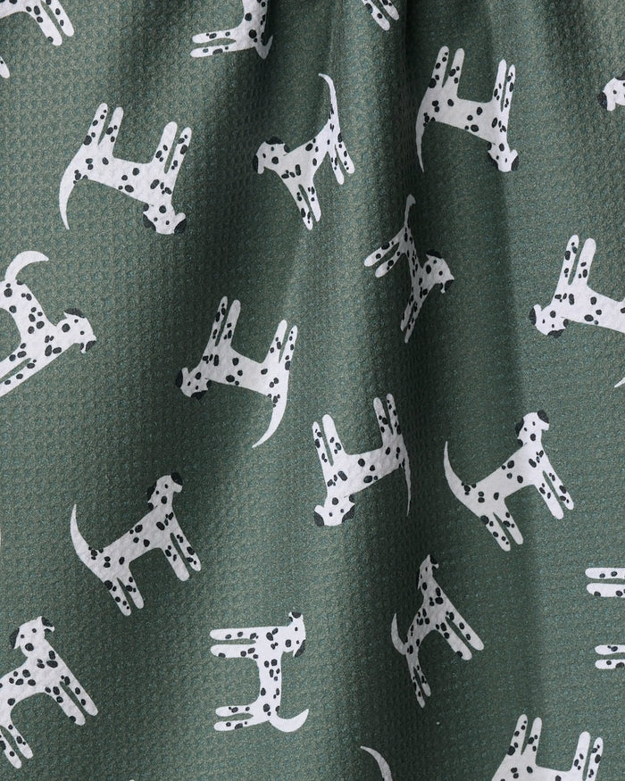 The Coit Creative Dalmation Dogs tea towel is green, textured, made from recycled materials, and features a repeating pattern of white cartoon Dalmatians with spots in various poses.