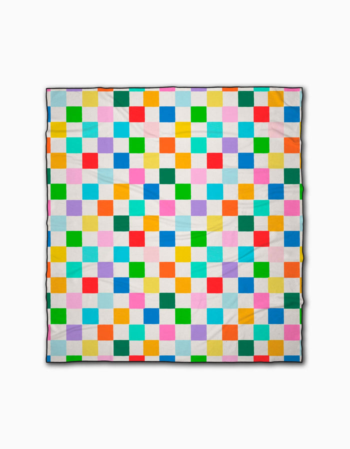 The Dance Floor quilt by Vaishali Design Studio features small, evenly sized bright squares in a grid on white. Crafted from quick-drying materials, it’s perfect as a beach blanket.
