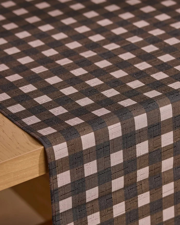 A close-up of a table with the Geometry Deep Hearth brown and beige stain-resistant table runner draped neatly over the edge.
