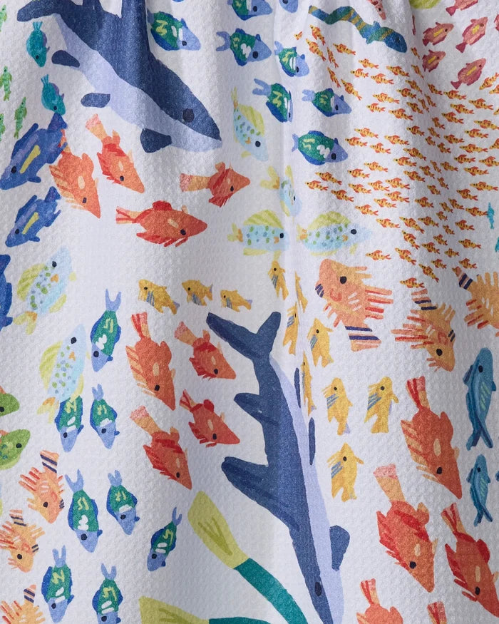 “Deep Sea Encounter” by Janna Sue Design features vibrant blue, orange, yellow, and green fish swimming on textured Geoweave fabric. A large blue fish stands out among smaller ones. Perfect as a colorful tea towel for your kitchen.