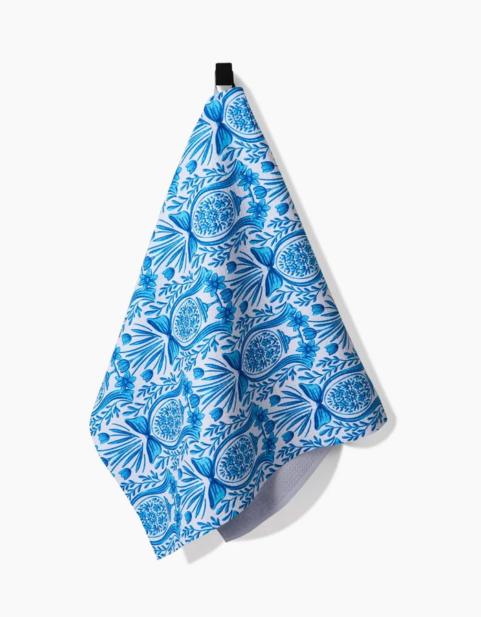 The Delft Blue Easter Egg Damask tea towel by Sarah Daugherty, featuring intricate blue and white floral and circular patterns, hangs from a black loop against a white background.