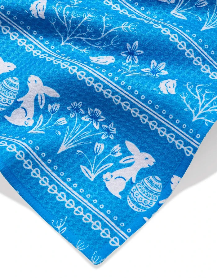 The Delft Blue Easter Stripe bar towel by Sarah Daugherty features bright blue Geoweave fabric with white rabbits, birds, eggs, flowers, and branches in horizontal rows—an elegant and festive accent for your kitchen.
