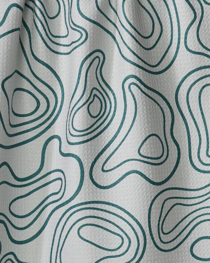 Close-up of Twig + Spark’s Depth Chart white textured fabric, featuring an abstract green contour line pattern inspired by topographic maps, flowing smoothly like a tea towel over the surface.