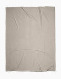 The GEOMETRY Desert Haze Butter Blanket, crafted from recycled materials in light beige with slight wrinkles, is laid flat on a white background.