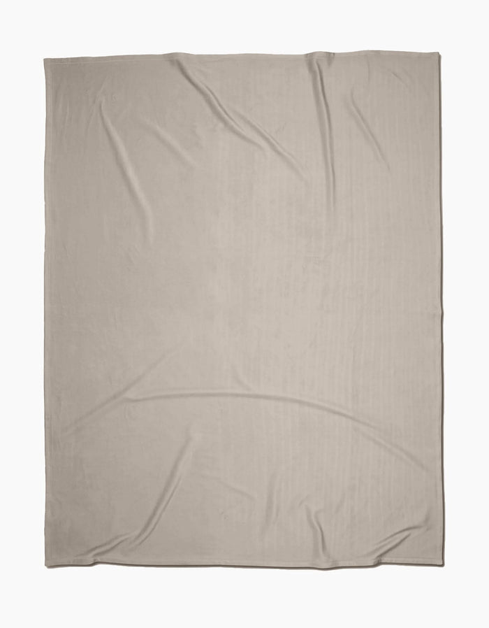 The GEOMETRY Desert Haze Butter Blanket, crafted from recycled materials in light beige with slight wrinkles, is laid flat on a white background.