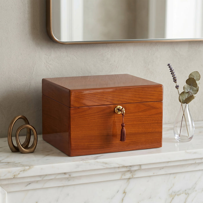 Wooden urn box with a tassel on a marble surface, next to decorative items.