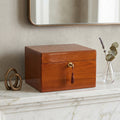 Wooden urn box with a tassel on a marble surface, next to decorative items.