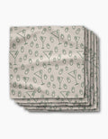 A stack of Rosa Kichline Dirty Martini beige recycled dinner napkins, featuring a repeating pattern of green martini glasses and olives.