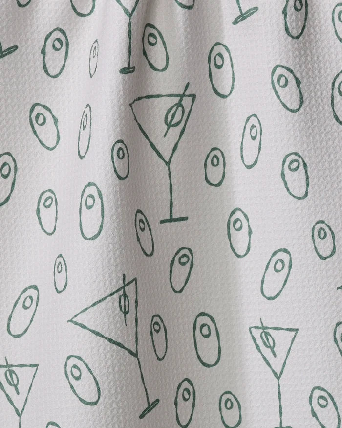 The Rosa Kichline "Dirty Martini" tea towel features a white textured fabric with green martini glass and olive line drawings. Quick-drying, it adds a playful touch to your bar or kitchen décor.