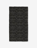The Dotty Black Luxe Bath Towel by GEOMETRY showcases evenly spaced small white dots on a rectangular black surface, made with ultra-absorbent Geoweave technology, displayed against a white background.
