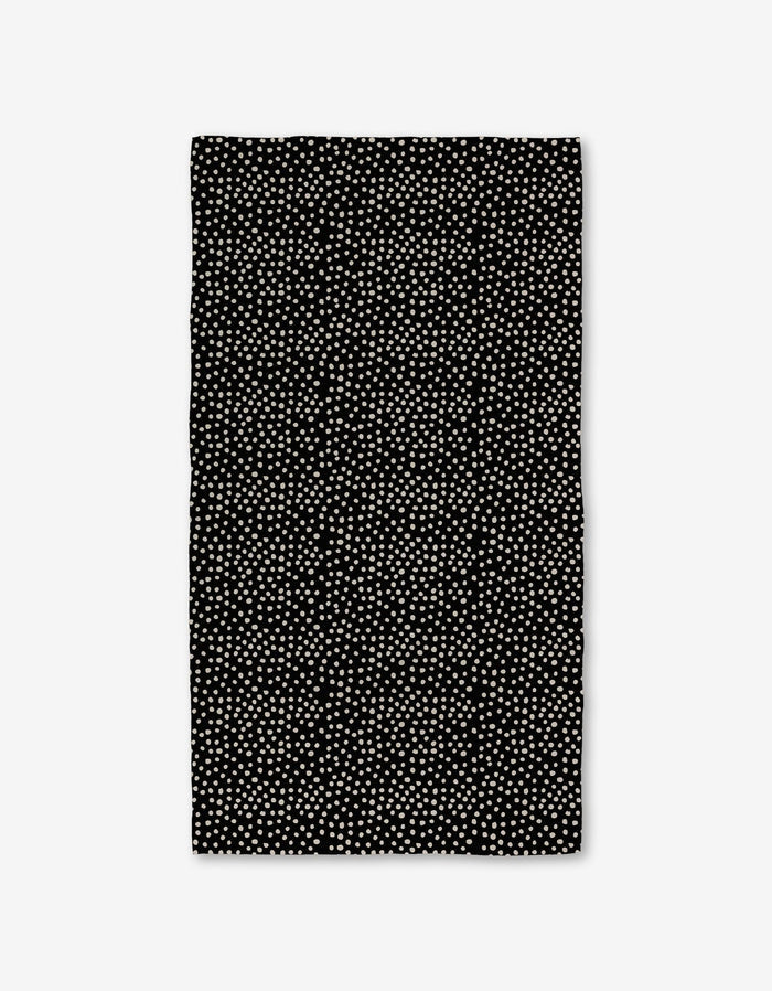 The Dotty Black Luxe Bath Towel by GEOMETRY showcases evenly spaced small white dots on a rectangular black surface, made with ultra-absorbent Geoweave technology, displayed against a white background.