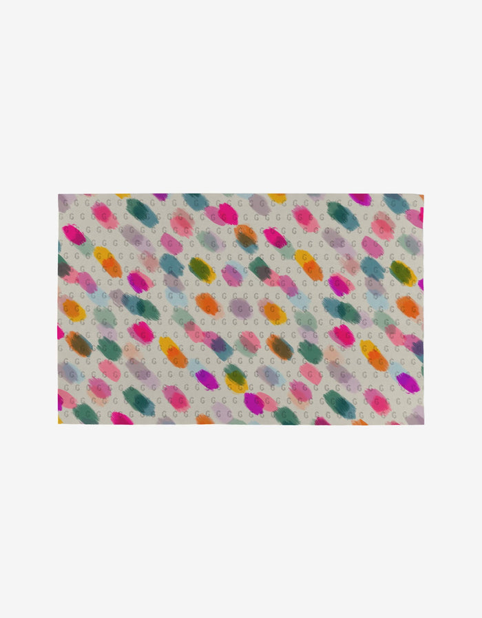 Downpour by GEOMETRY is a rectangular fabric featuring colorful paint-like splotches and small gray “G” letters on a light background, made from post-consumer recycled materials for an eco-friendly towel alternative.