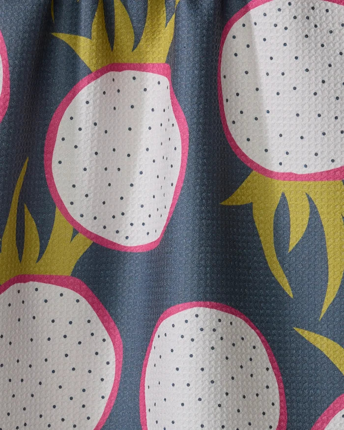 Dragon Fruit Frolic by Lizzie Clark is a quick-drying tea towel with large white dragon fruits, pink borders, black dots, and yellow-green leaves on a dark blue background.