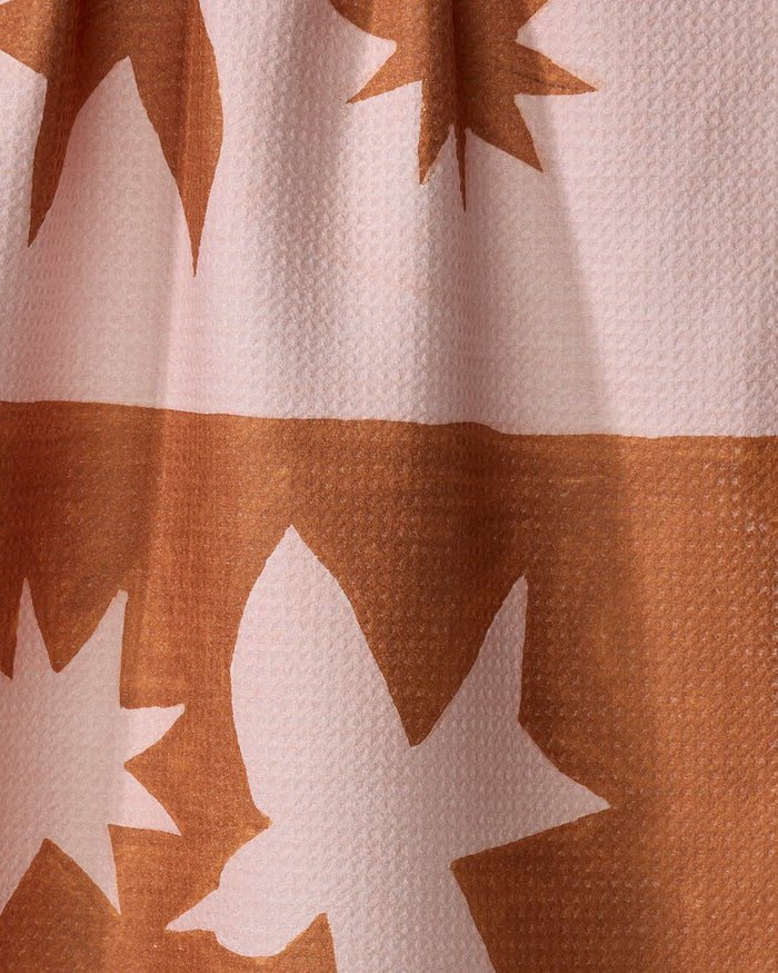 A close-up of the quick-drying Duality fabric by Jen B. Peters, featuring sharp, angular brown and white bird-like shapes on a textured light pink background—an abstract, modern design perfect for tea towels.